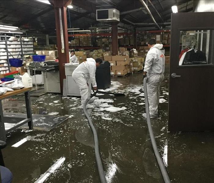 uniformed workers cleaning water damage at a factory